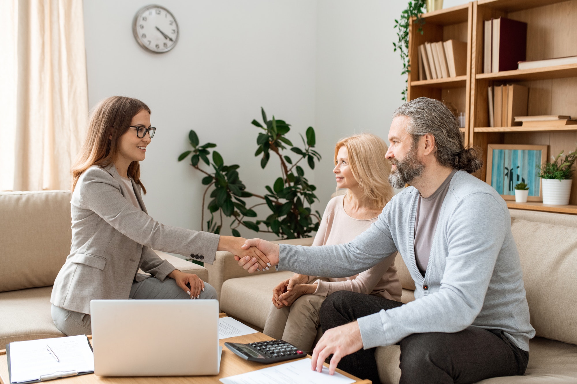 casual bearded man shaking hand of young female real estate agent over desk.jpg